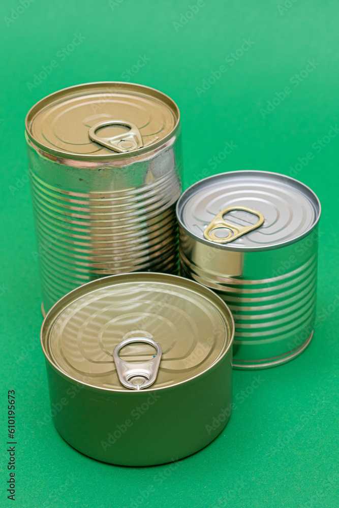 A Group of Stacked Tin Cans with Blank Edges on Green Background. Canned Food. Different Aluminum Cans for Safe and Long Term Storage of Food. Steel Sealed Food Storage Containers A Group of Stacked Tin Cans with Blank Edges on Green Background. Canned Food. Different Aluminum Cans for Safe and Long Term Storage of Food. Steel Sealed Food Storage Containers