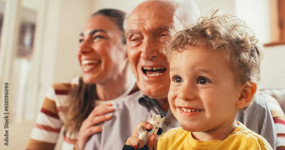 Portrait of a Small Family of a Mother, a Son and a Grandfather Watching TV Together in the Living Room. Family Generations Connecting and Bonding by Spending Time Together, Discussing and Having Fun Portrait of a Small Family of a Mother, a Son and a Grandfather Watching TV Together in the Living Room. Family Generations Connecting and Bonding by Spending Time Together, Discussing and Having Fun