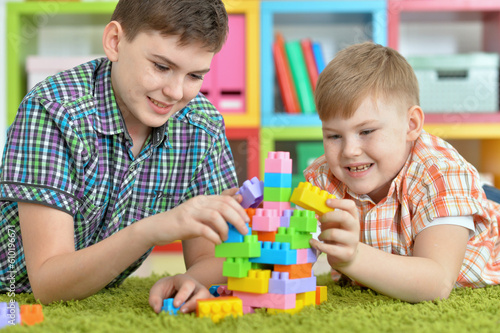 brothers playing with colorful plastic blocks in room