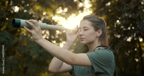 Hiker standing in the forest and looking through telescope