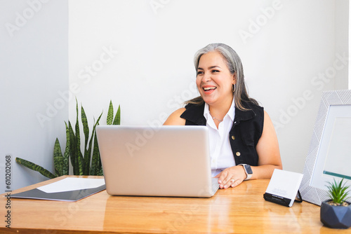 Latin executive woman with gray hair working with laptop