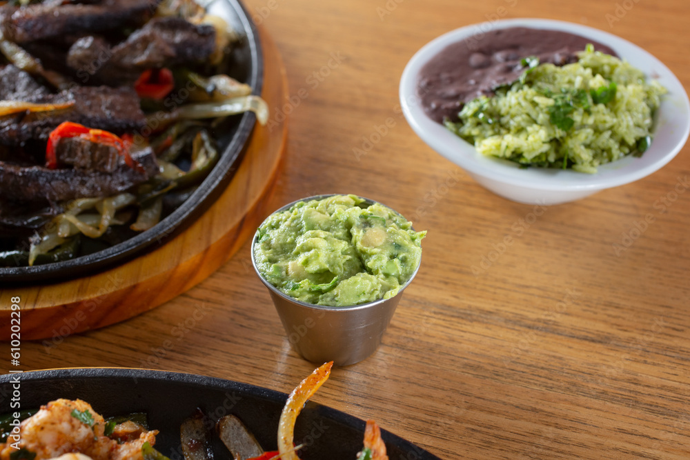 A view of a metal condiment cup of guacamole. A view of a metal condiment cup of guacamole.