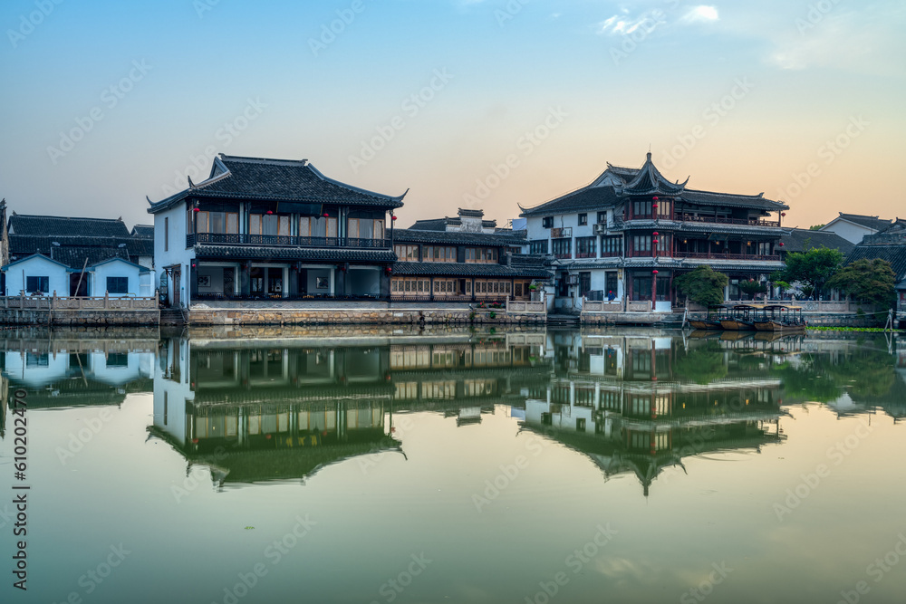 landscape with Chinese ancient town, wooden houses and smooth lake in sunrise
