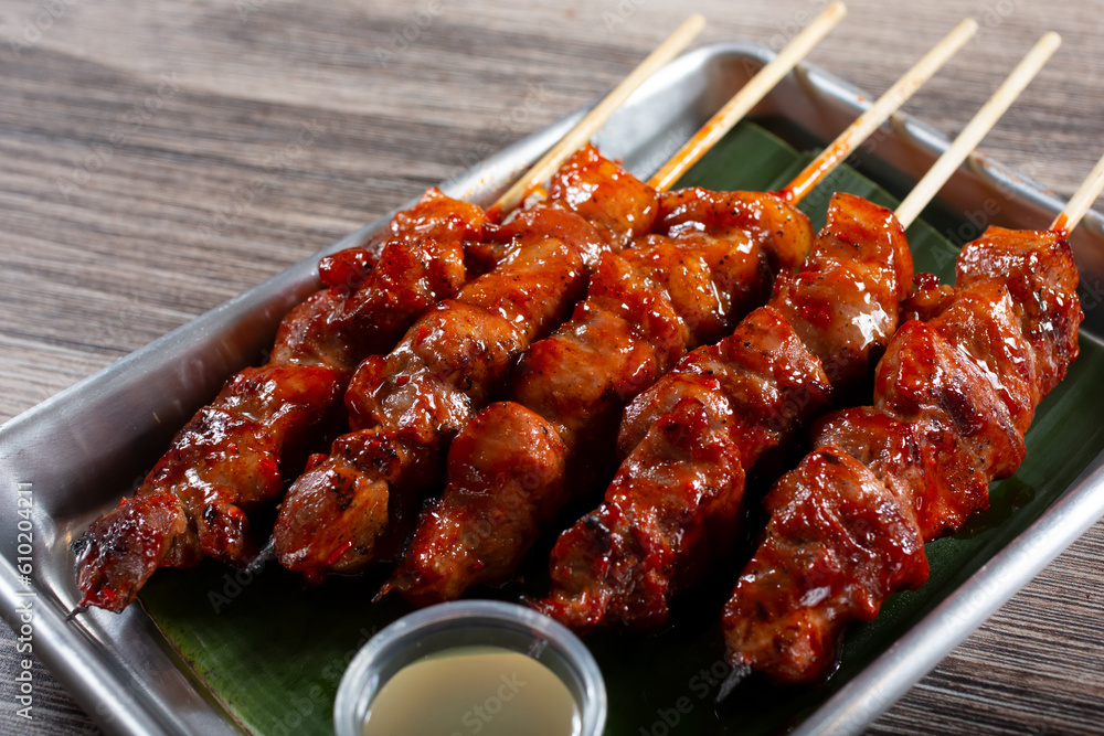 A view of a tray of BBQ pork skewers.