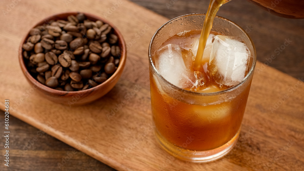 Pouring black coffee in glass with ice. Making iced coffee Pouring black coffee in glass with ice. Making iced coffee