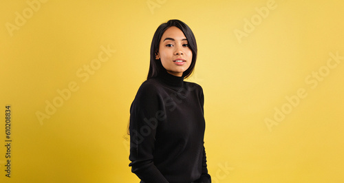 Girl Wearing Black Knitted Jumper Isolated on Yellow Background Pointing and Looking for Fashion Sales, product sales, Product Presentation, Advertising, Branding, Graphic Design, Web Design, Fashion  © ARTMAXX
