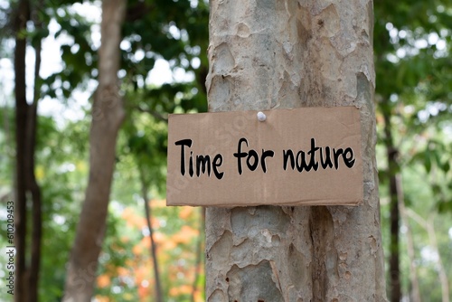 Cardboard from boxes cover with texts ' Time for nature', was sticked on tree bark to call out all people to care about and to beat the pollution from plastic.