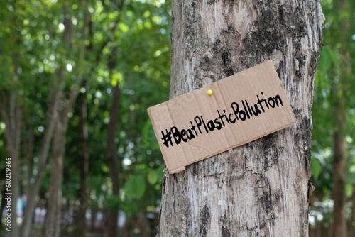 Cardboard from boxes cover with texts ' BeatPlasticPollution', 2023 world environment day motto, was sticked on tree bark to call out all people to care about and to beat the pollution from plastic. © Sophon_Nawit