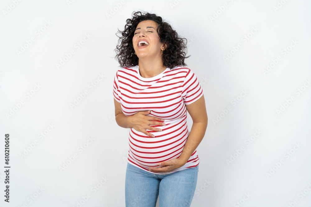 Φωτογραφία young pregnant woman wearing striped t-shirt over white background smiling and laughing hard out loud because funny crazy joke with hands on body