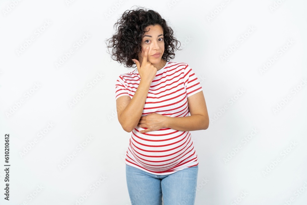 Φωτογραφία young pregnant woman wearing striped t-shirt over white background Pointing to the eye watching you gesture, suspicious expression