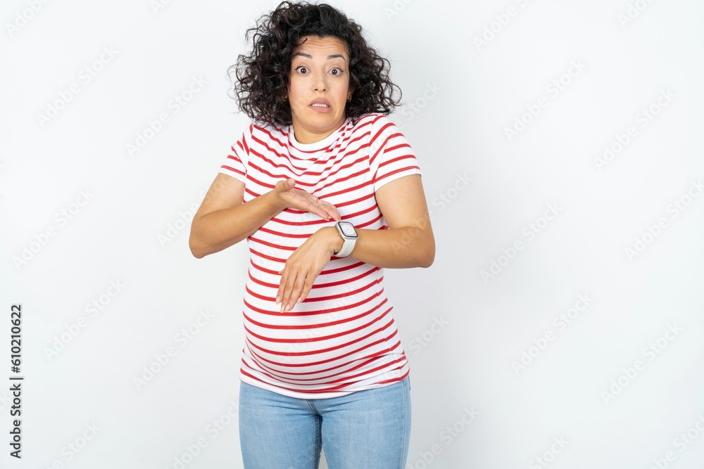 young pregnant woman wearing striped t-shirt over white background In hurry pointing to watch time, impatience, upset and angry for deadline delay. young pregnant woman wearing striped t-shirt over white background In hurry pointing to watch time, impatience, upset and angry for deadline delay.
