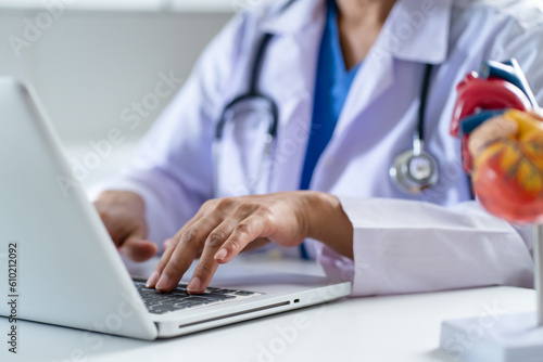 Doctor consult patient on laptop with anatomical model of human heart Cardiologist supports the heart Online doctor appointment..