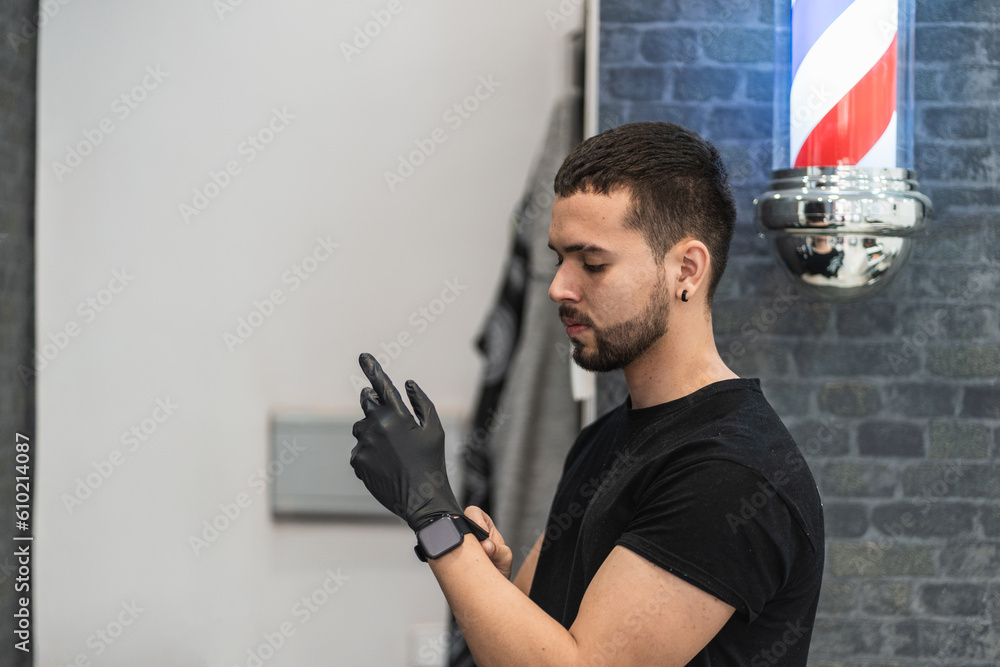 Foto de Barber putting a black nitrile glove on his hand to start
