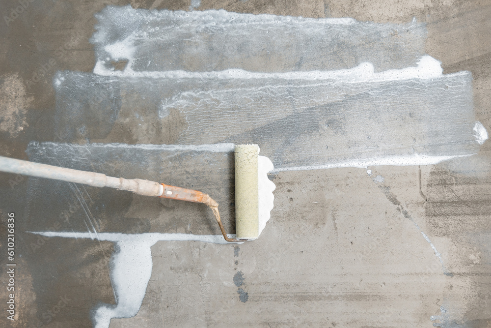 Closeup floor priming process, top view. Worker use primer on concrete