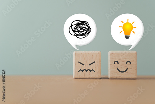 wooden cube blocks with unhappy face and happy, a tangle of thoughts and brighten lightbulb on white speech bubble, for creative, solution, problem solving conceptTwo wooden cube blocks with unhappy f