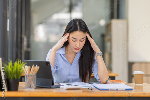 Portrait of tired young business Asian woman work with documents tax laptop computer in office. Sad, unhappy, Worried, Depression, or employee life stress concept 