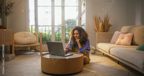 Quadro su tela Portrait of Smiling Young Woman Working from Home on Laptop Computer in Sunny Cozy Apartment