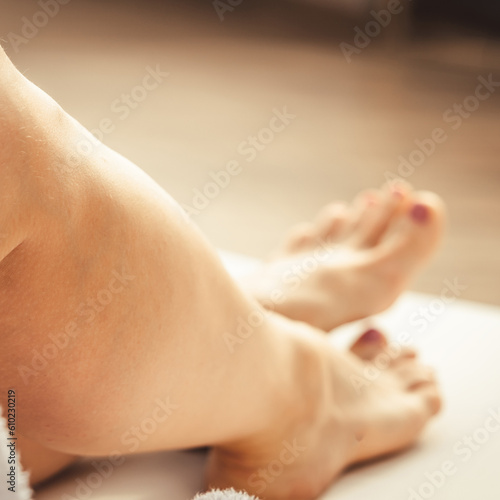 Womans feet in white bathrobe lying on sofa and relaxing at the roof.