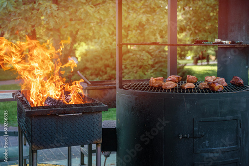 Sizzling juicy pieces of beef steak roast on hot iron grill outdoor. Bright flame burning at street cafe for meat preparation outdoor. photo