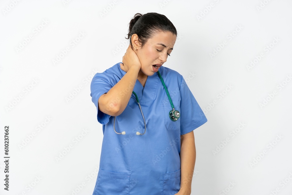 Young doctor woman wearing blue uniform over isolated background Suffering of neck ache injury, touching neck with hand, muscular pain Young doctor woman wearing blue uniform over isolated background Suffering of neck ache injury, touching neck with hand, muscular pain