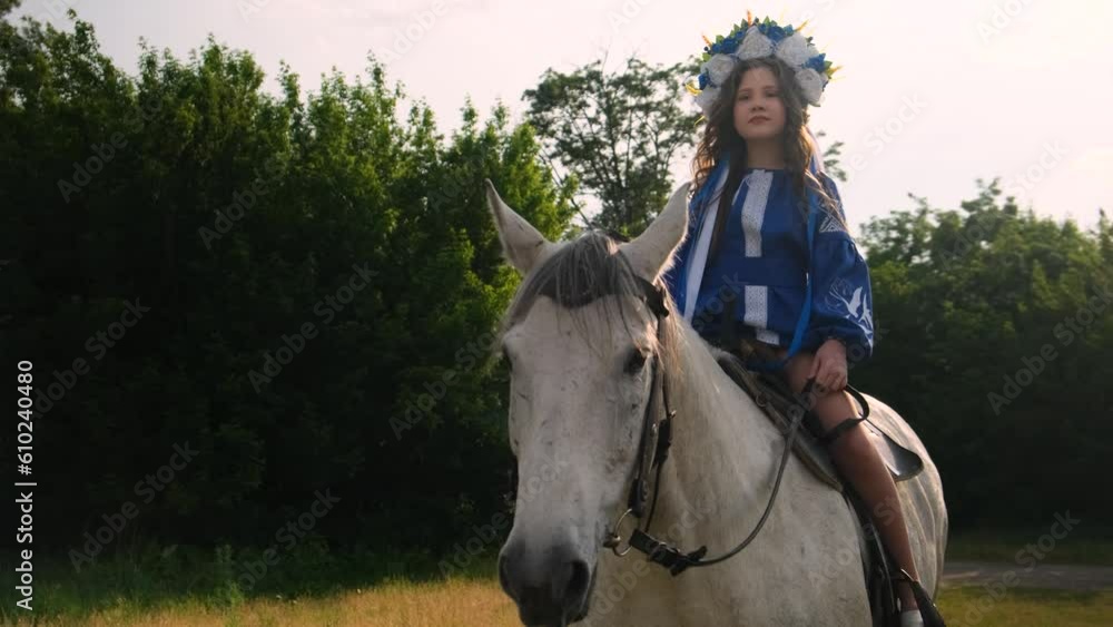 A young girl, in a beautiful Ukrainian national dress, rides a white horse. A young girl, in a beautiful Ukrainian national dress, rides a white horse.