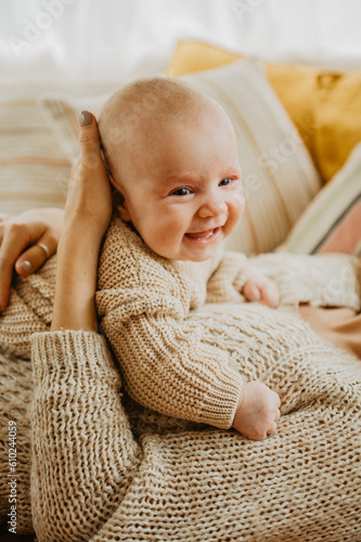Newborn baby girl smiles and laughs on the bed. Orange and beige colors.