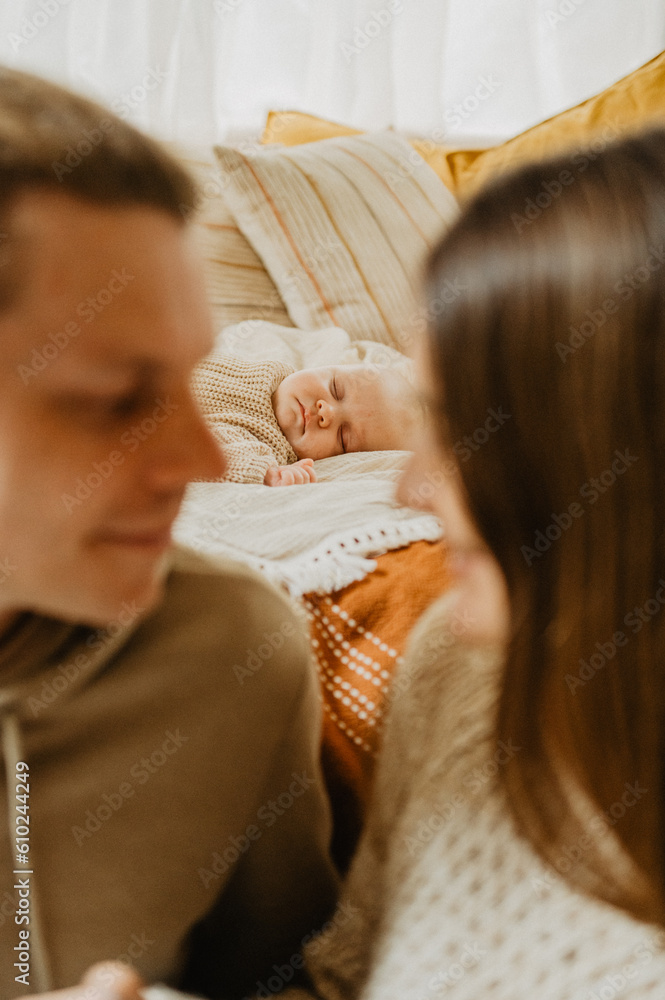 Fototapeta premium Young mother and father with their little daughter hugging and kissing on the bed.
