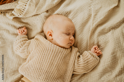 A newborn girl sleeps on the bed. Orange and beige colors.
