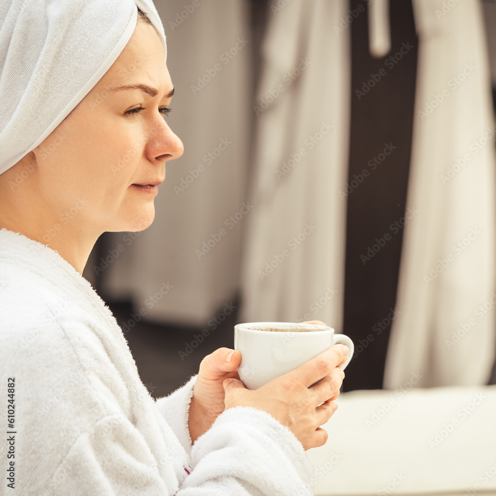Woman in white bathrobe and towel lying on sofa and relaxing with tea at the roof. Woman in white bathrobe and towel lying on sofa and relaxing with tea at the roof.