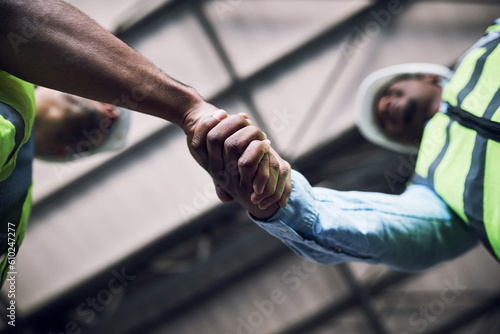 People, architect and handshake in construction, hiring or building in teamwork partnership on site. Low angle of contractor or engineer shaking hands in recruiting, architecture agreement or deal