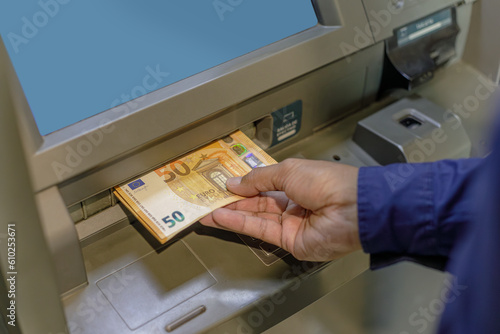 A man's hand extracting euros from an ATM. photo