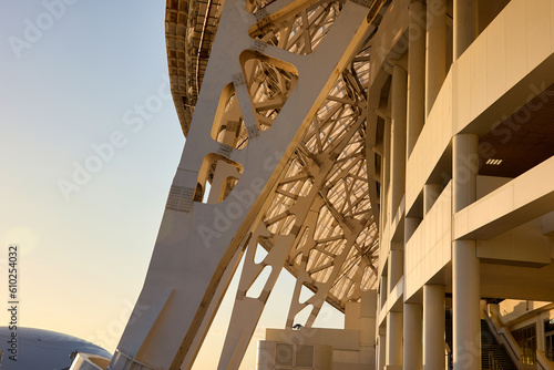 Part of the exterior concrete structure of a large stadium at sunset. Huge metal support and concrete base of the stadium stand