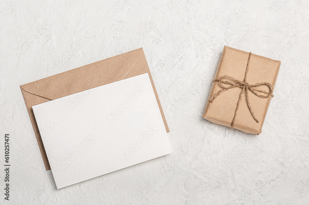 Invitation or greeting card mockup, craft envelope with craft gift box on light background. Blank postcard. Invitation or greeting card mockup, craft envelope with craft gift box on light background. Blank postcard.