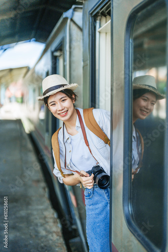 Asian teenage girl traveling using a camera take a photo to capture memories while waiting for a train at the station.