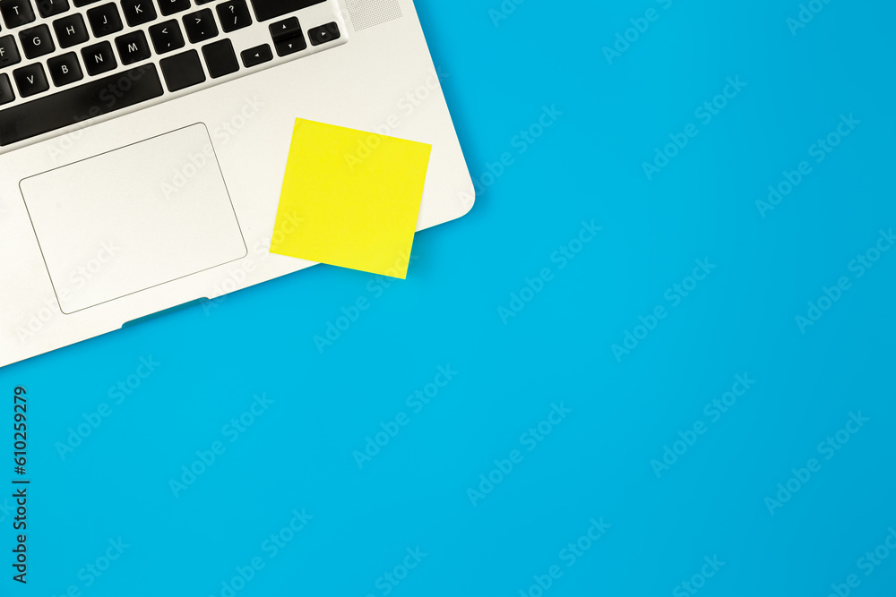 Notebook and yellow paper reminder on blue background, copy space. Notebook and yellow paper reminder on blue background, copy space.