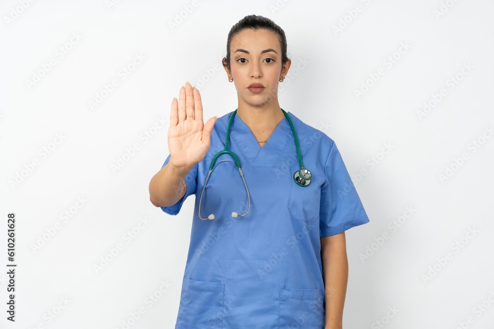 Beautiful doctor woman standing over white studio background doing stop sing with palm of the hand. Warning expression with negative and serious gesture on the face.