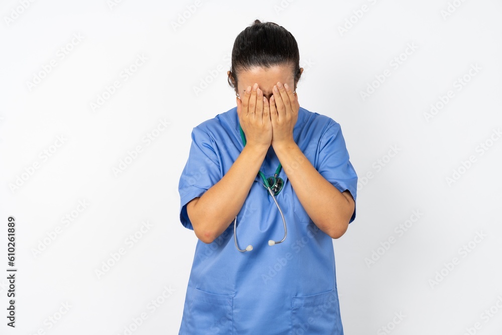 Beautiful doctor woman standing over white studio background covering her face with her hands, being devastated and crying. Sad concept Beautiful doctor woman standing over white studio background covering her face with her hands, being devastated and crying. Sad concept