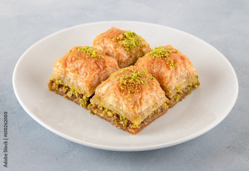 Pistachio Turkish baklava on a white plate.Close-up of four slices of baklava
Pistachio Turkish baklava on a white plate.Close-up of four slices of baklava