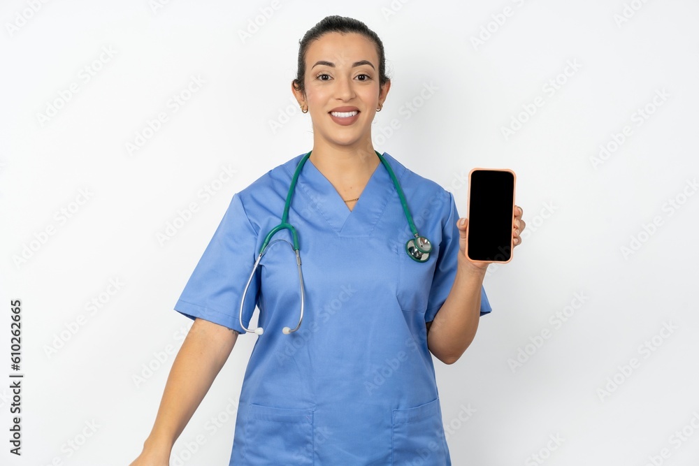 Smiling Beautiful doctor woman standing over white studio background Mock up copy space. Hold mobile phone with blank empty screen Smiling Beautiful doctor woman standing over white studio background Mock up copy space. Hold mobile phone with blank empty screen