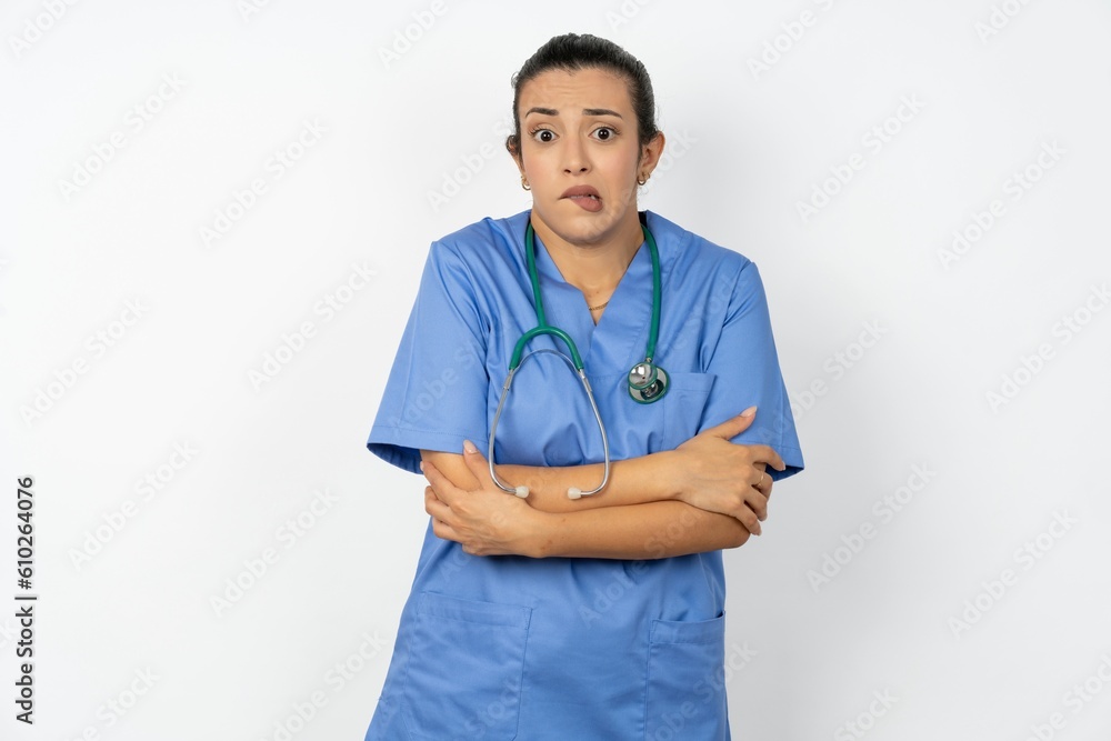Beautiful doctor woman standing over white studio background shaking and freezing for winter cold with sad and shock expression on face. Beautiful doctor woman standing over white studio background shaking and freezing for winter cold with sad and shock expression on face.
