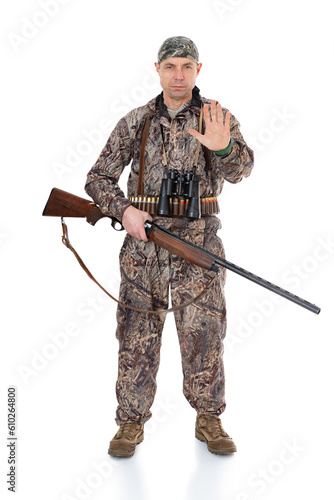Duck hunter with a rifle and binoculars doing stop sing with palm of the hand. Fifty-year-old man in hunting uniform standing in studio, isolated on white background. Full length portrait of a hunter.