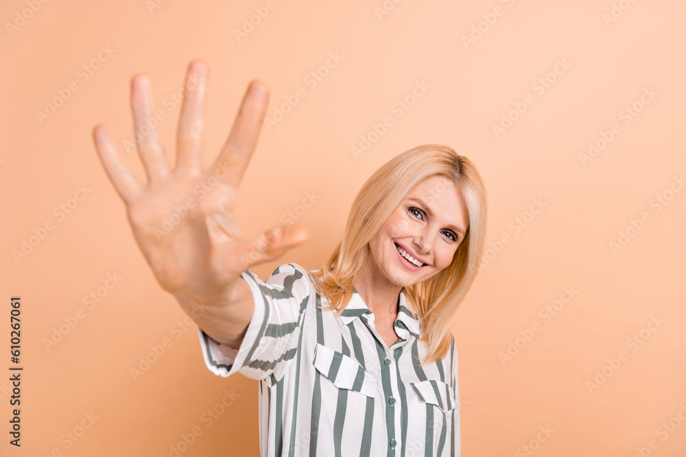 Portrait of cheerful optimistic retired woman blond hairdo striped formalwear showing highfive to you isolated on beige color background Portrait of cheerful optimistic retired woman blond hairdo striped formalwear showing highfive to you isolated on beige color background