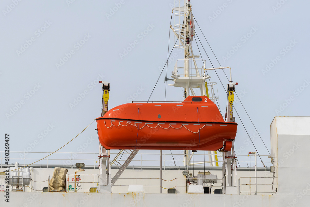 Lifeboat on big cargo vessel. Lowering orange lifeboat to water. Abandon ship drill. Lifeboat