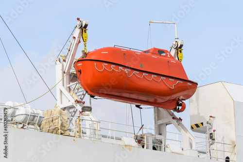 Lifeboat on big cargo vessel. Lowering orange lifeboat to water. Abandon ship drill. Lifeboat training. Man over board drill. Lifeboat training. photo