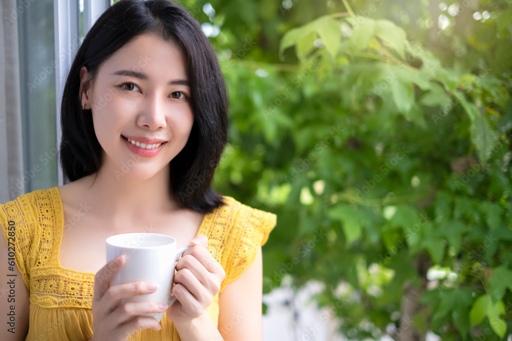 Happy woman standing by window smiling with cup of coffee. Happy woman standing by window smiling with cup of coffee.