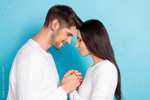 Photo of two pleasant adorable optimistic couple people wear white shirts holding hands together isolated on blue color background