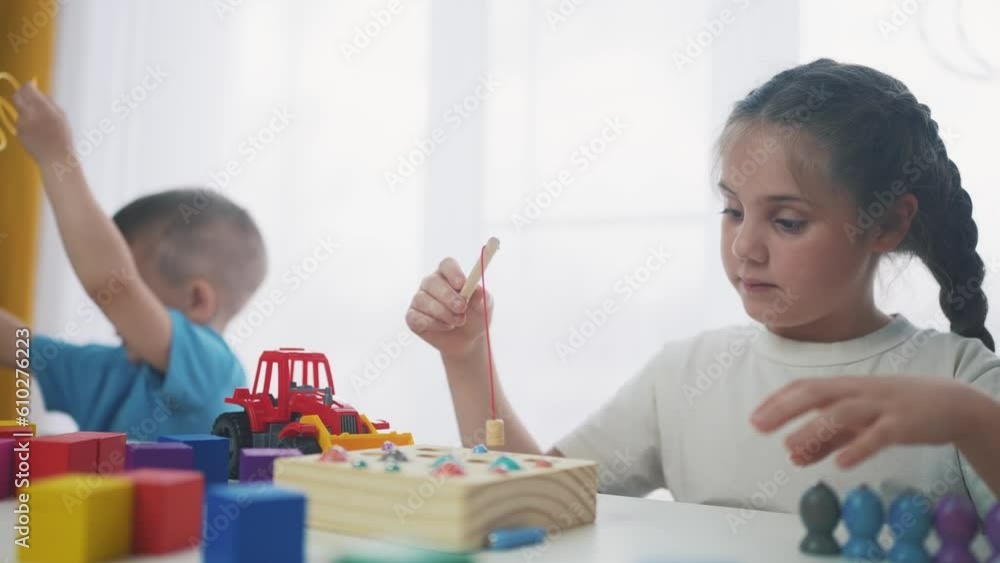 children at the table in kindergarten play an educational game fishing. development of fine motor skills in children. children play educational game catch fish in kindergarten. game dream kid concept children at the table in kindergarten play an educational game fishing. development of fine motor skills in children. children play educational game catch fish in kindergarten. game dream kid concept