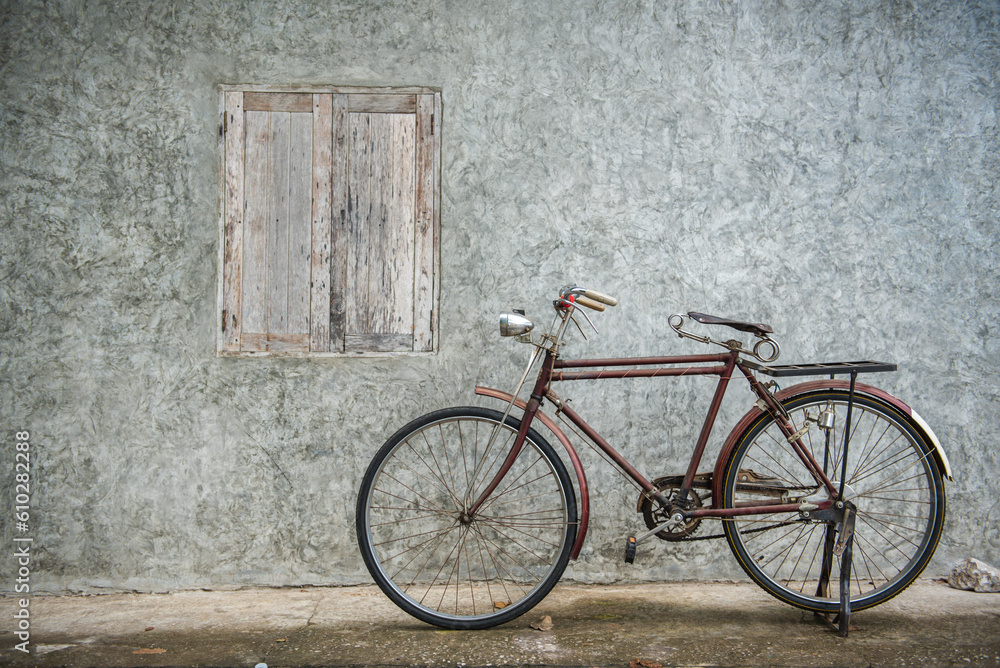 Vintage bicycle on old rustic dirty wall house, many stain on wood wall. Classic bike old bicycle on decay brick wall retro style. Cement loft partition and window background.