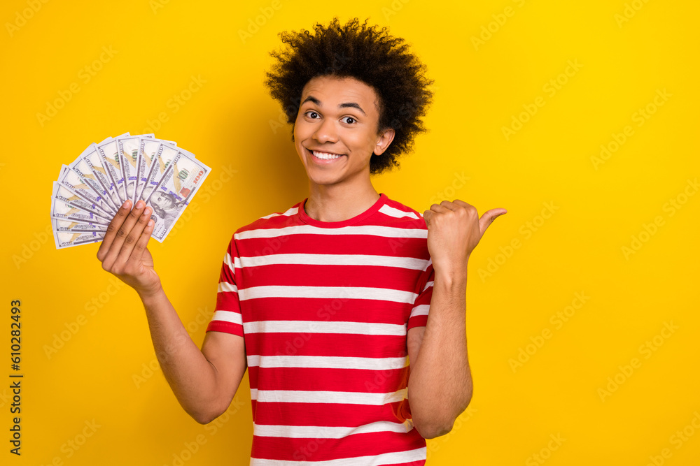 Photo of cheerful person hand hold dollar bills banknotes direct finger empty space isolated on yellow color background Photo of cheerful person hand hold dollar bills banknotes direct finger empty space isolated on yellow color background
