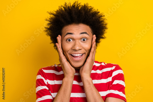 Photo of astonished person arms touch cheekbones beaming smile isolated on yellow color background
